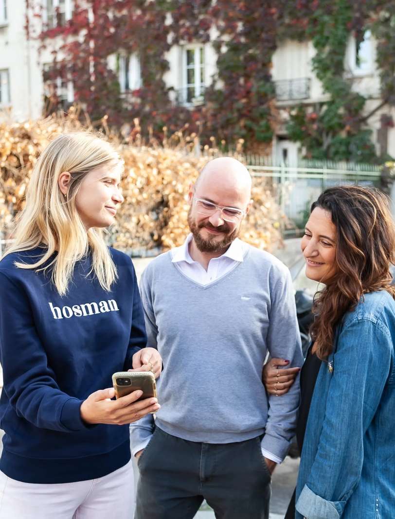 Un expert Hosman présente son application à deux clients, dans une rue parisienne
